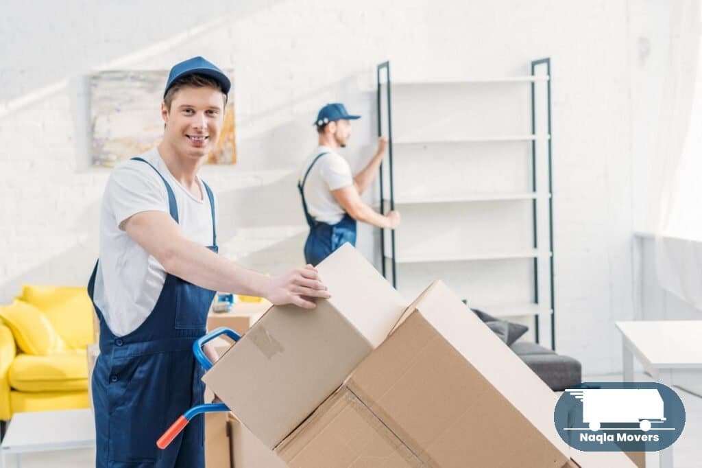 Naqla Movers crew transporting cardboard boxes and furniture in a Dubai apartment