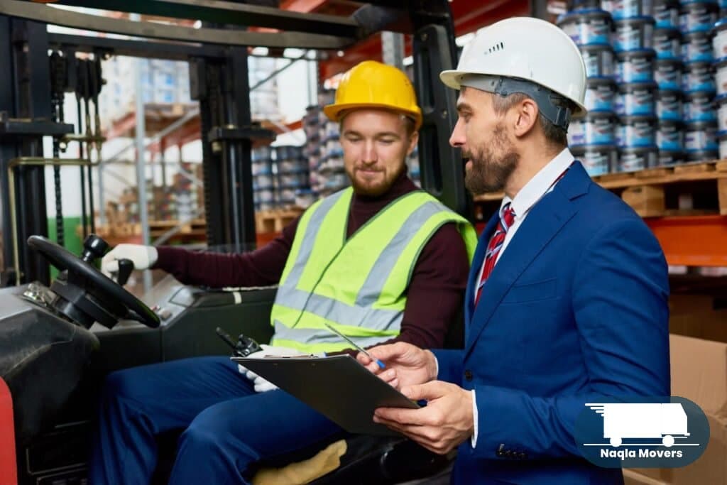 Naqla Movers warehouse supervisor briefing a crew member before dispatch